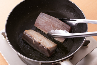 かつおをフライパンに入れ、表面を10秒ずつ焼き、全体に焼き色をつける（油跳ねするようならふたをする）。粗挽き黒こしょうをたっぷりとふり、全体にまぶして器に盛る。小鍋にバターレモンソースの材料を入れて中火にかけ、少し煮詰めてかつおステーキにかける。取り出しておいたにんにくを散らし、つけ合わせのクレソン、焼きれんこん（薄い輪切りにしてオリーブ油をからめ、魚焼きグリルでこんがり焼いて塩をふる）を添える。