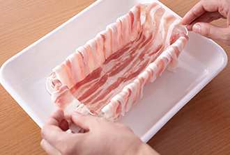 ボウルにひき肉だねの材料を入れて練る。豚もも肉はほぐして粗挽き黒こしょうを混ぜ合わせる。ローリエ1枚を半分にちぎってパウンド型の底に置き、その内側に豚バラ肉をはりつけるように、少しずつ重ねながら縦横に敷く。はみ出した肉は型の外側にたらしておく。