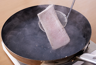 フライパン（または鍋）に湯を沸かし、マグロを入れる。表面全体が白くなったらすぐにひき上げ、水にさらして水気を拭く。