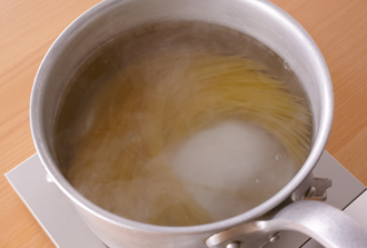 鍋に湯を沸かし、塩を入れる（分量外/湯2リットルに対して塩大さじ1と1/2）。スパゲッティを入れ、袋の表示時間を目安にゆで始める。トマトはへたを取って湯むきをしてから、ざく切りにする。