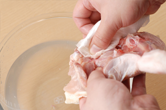 オーブンを230℃に温め始める。鶏肉は、骨のまわりの血のついた部分や汚れなどをよく洗い、水けを拭く。