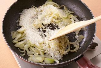 フライパンにオリーブ油を中火で熱し、玉ねぎ、にんにくを入れて炒める。玉ねぎがしんなりしたら、米を洗わずに加えてさっと混ぜる。