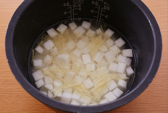 炊飯釜に米と酒、塩を入れ、2合の目盛りまで水（分量外）を加える。大根、しょうが（せん切り）をのせて普通に炊く。