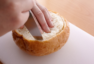 パンの内側を1センチほど残してナイフを刺し込み、丸く切り込みを入れる。パンの底が抜けないように気をつけて中のパンを取り出す。