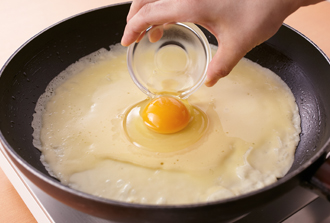 フライパンにサラダ油少々を入れて中火にかけ、しっかり熱したら弱火にして生地の1/2量を流し入れる。生地が固まらないうちに卵を真ん中に落とし入れ、チーズを散らしてふたをする。