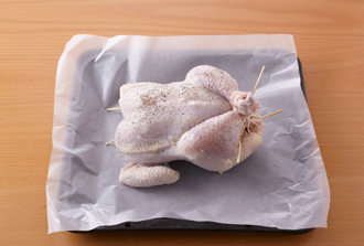 天板にオーブン用シートを敷いて鶏をのせ、200度に予熱したオーブンで40分ほど焼く。途中、鶏から出てきた脂を刷毛で表面に塗りながら焼くと、きれいな焼き色がつく。