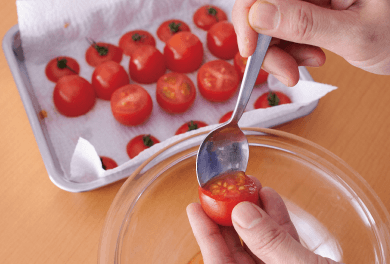 ミニトマトは、へたから4分の1のところで切る。下の部分をスプーンでくり抜き、中身を出してペーパータオルの上にのせ、汁けをきっておく。
