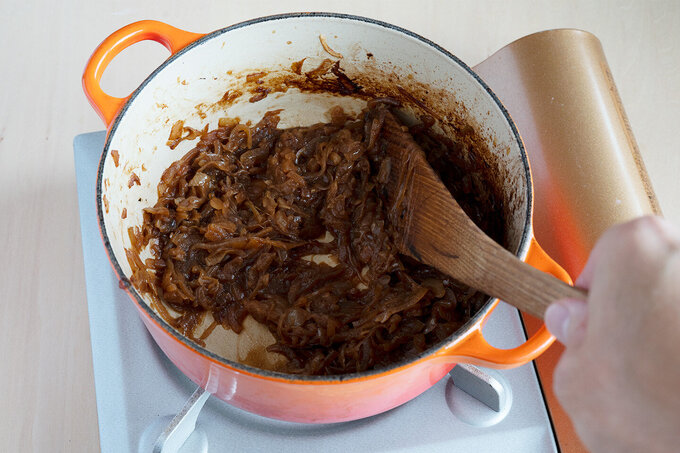 厚手の鍋にオリーブ油を入れて強めの中火で熱し、玉ねぎ、にんにくを入れて炒める。玉ねぎが焦げてきたら水 大さじ3〜4（分量外）を入れ、焦げすぎないようにする。これを繰り返しながら20分ほど炒め、濃い茶色にする。