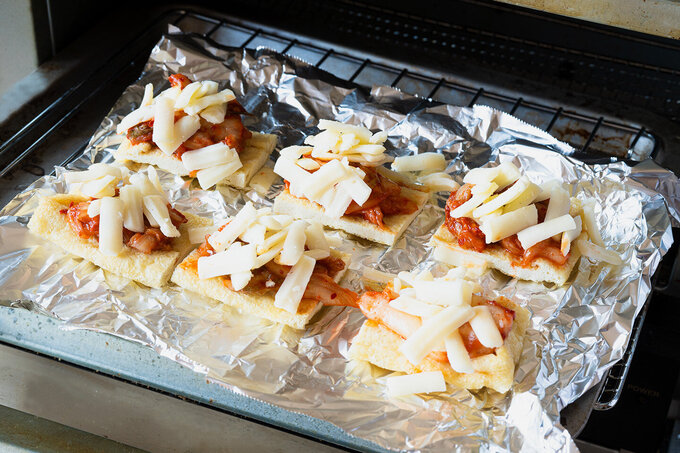 オーブントースターの天板にアルミホイルを少しくしゃっとさせてから広げ、油揚げを並べる。白菜キムチ、ピザ用チーズを等分にのせ、オーブントースターでチーズが溶けるまで5分ほど焼く。