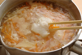 鍋に湯と鶏ガラスープの素を入れて強火にかける。煮立ったらにんにく、しょうが、たけのこ、にんじんを入れる。再び煮立ったらタラを加え、色が変わって火が通ったら、菜箸でこまかくほぐす。身をほぐすことで、タラのうまみがスープに加わり、おいしくなる。