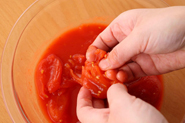 トマトの水煮の果肉は意外につぶしにくいもの。いったんボウルに入れ、へたを外して果肉を軽く手でつぶしておきましょう。