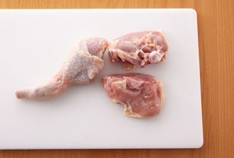 鶏肉は関節の間に包丁を入れて切り分け、さらに、上の部分は骨に添って包丁を入れ、全部で3つに切り分ける。