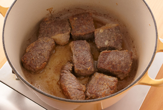 玉ねぎは薄切りにする。牛肉は塩、こしょう各少々をふって小麦粉を薄くまぶす。鍋にバターの1/2量を中火で溶かし、牛肉を入れて全体がこんがりするまで焼きつけて取り出す。
