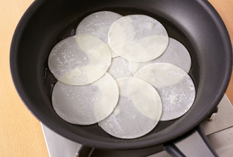 フライパンにサラダ油をしく。中央に餃子の皮を1枚置き、周りに餃子の皮7枚を少しずつ重ねながら丸く並べる。