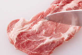 豚肉は包丁の先で白い脂肪と肉の間に細かく切り込みを入れ、筋切りをする。