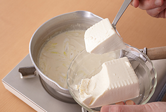 豆腐をスプーンでおおまかにすくって入れ、豆乳を沸騰させないように温めたら器に盛り、すりおろしたゆずの皮、一味唐辛子をふる。
