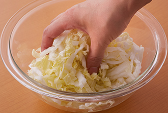 白菜は縦半分に切ってからせん切りにしてボウルに入れ、塩をまぶして水気が出るまでおく。