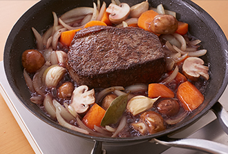 牛肉を戻し入れ、赤ワインを加えてしっかり煮立たせる。水を加え、ふたをして弱火で10分、牛肉の上下を返してさらに10分蒸し煮にする。肉を取り出し、粗熱を取る。残った汁は、とろみがつくまで野菜ごと少し煮詰めてソースにする。肉は厚さ１センチのそぎ切りにして器に盛り、野菜を添えてソースをかけ、パセリを散らす。