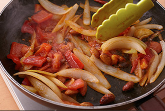 空いたフライパンにサラダ油大さじ1を入れ、玉ねぎ、にんにく、赤唐辛子を加えて中火で炒める。玉ねぎがしんなりしたらパプリカ、アーモンド、レーズン、トマトを加え、ときどき混ぜながらトマトが煮くずれるまで炒めて火を止める。