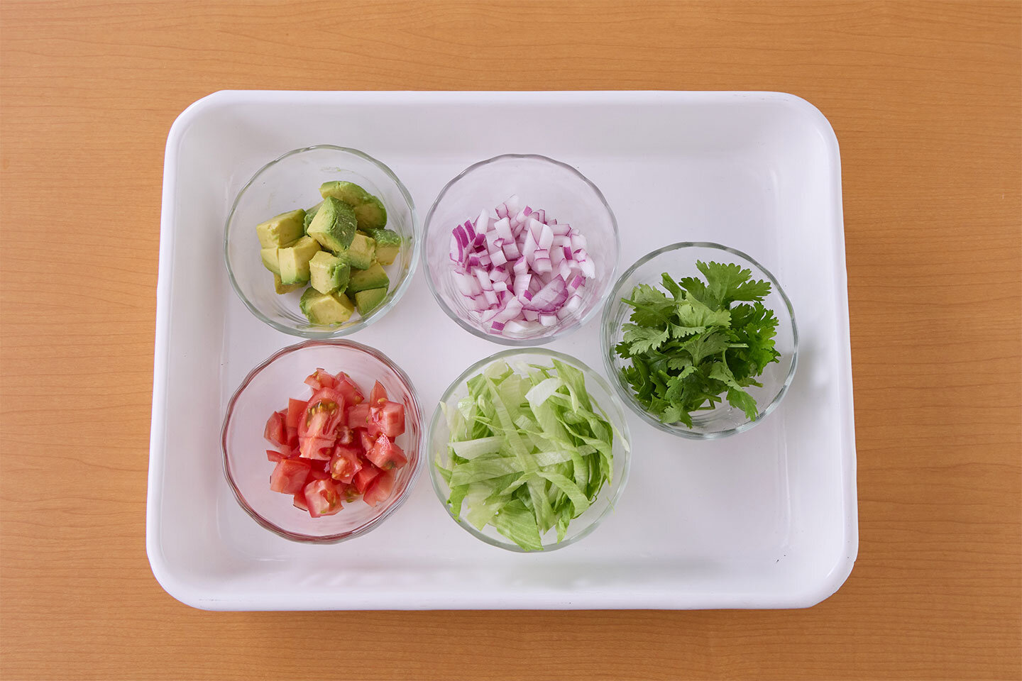 トッピングの準備をする。アボカドは1.5㎝角、トマトは1㎝角に切る。紫玉ねぎは粗いみじん切り、レタスは細切りにし、パクチーは長さ2㎝に切る。タコスシェルに2をのせ、好みのトッピングをのせる。