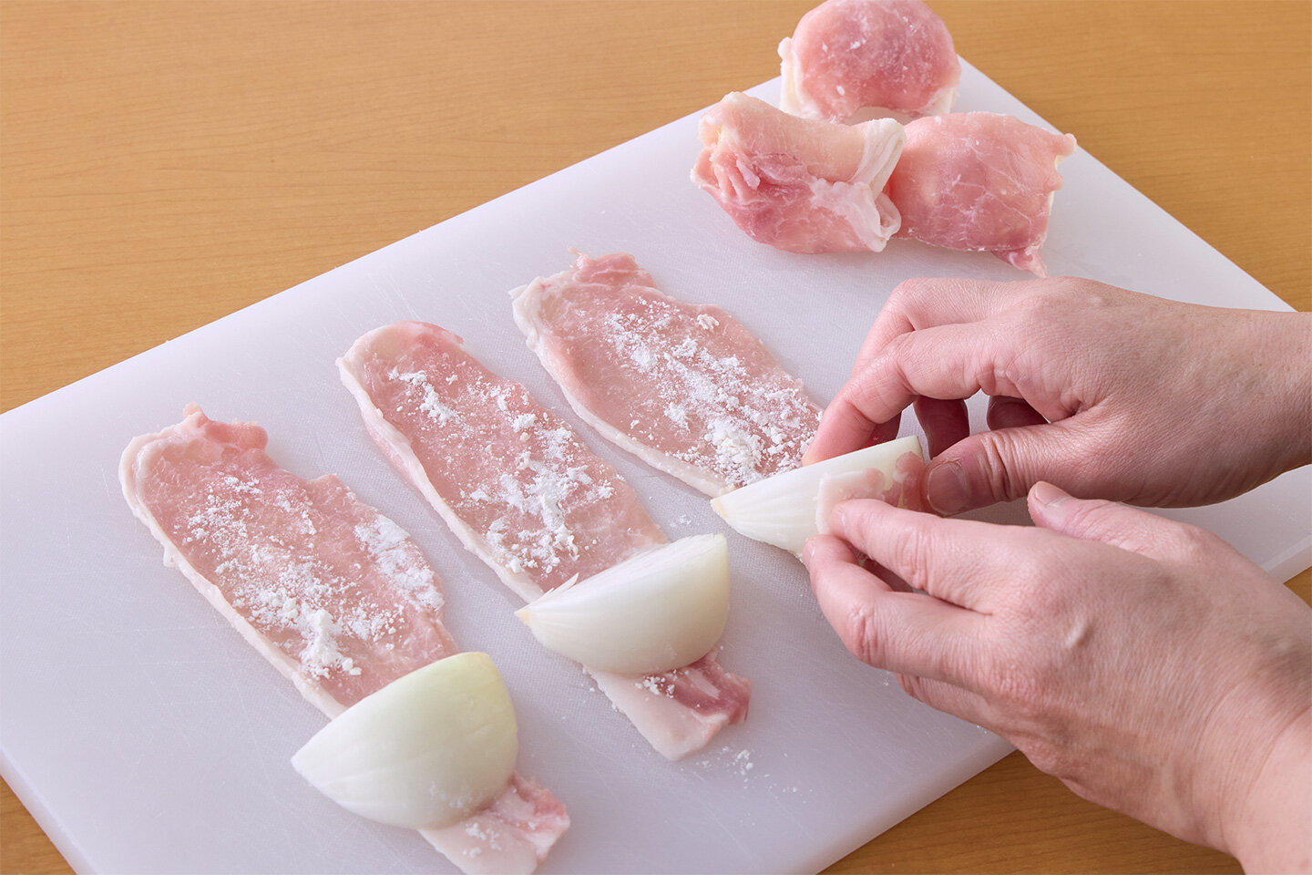 玉ねぎは6等分のくし形に切り、小麦粉をまぶす。豚肉を、手前に細い部分がくるように縦長に置き、手前に玉ねぎを置いてくるくると巻く。Aを混ぜておく。